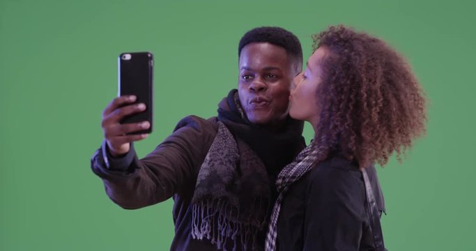 Young black man and woman pose for a selfie on green screen. On green screen to be keyed or composited. 