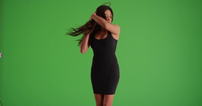Portrait of Latina female in tight black dress dancing sensually on green screen. On green screen to be keyed or composited. 