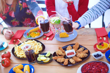 Top view of group of people having dinner together while sitting at wooden table. Food on the table. People eat fast food.