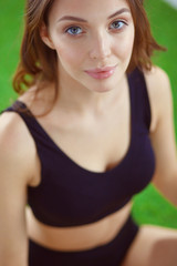 Fototapeta premium Woman sitting with crossed legs on the green grass.