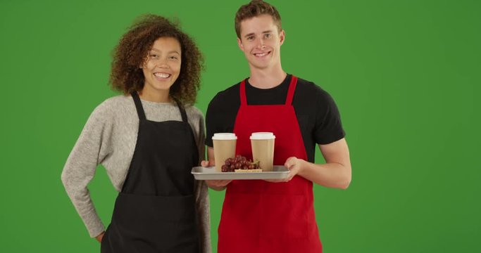Portrait of two waiters at outdoor food truck or cafe with tray of food and drinks smiling on green screen. On green screen to be keyed or composited. 