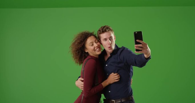 Cute couple taking selfie with cell phone on green screen. On green screen to be keyed or composited. 