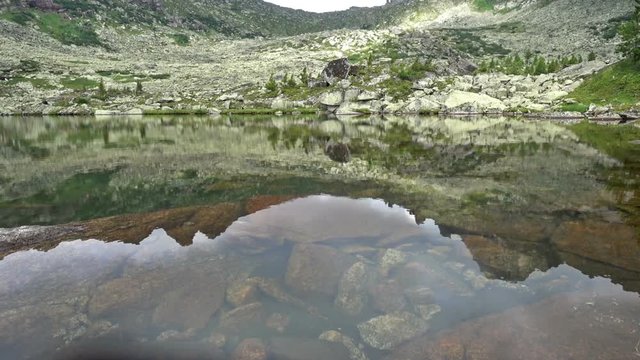 Rocky peaks are reflected in a mountain lake. Western Siberia, Ergaki range. 