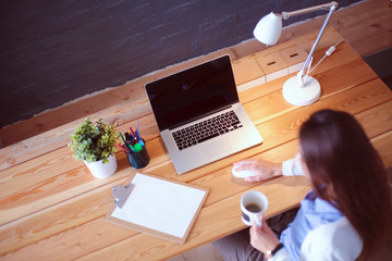 Portrait of relaxed young woman sitting at her desk holding cup of coffee. Business Woman. Workplace