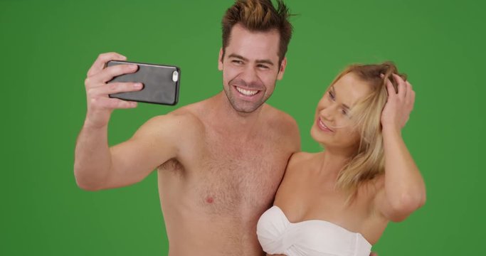 Young social media obsessed couple taking selfies to post online on green screen. On green screen to be keyed or composited. 