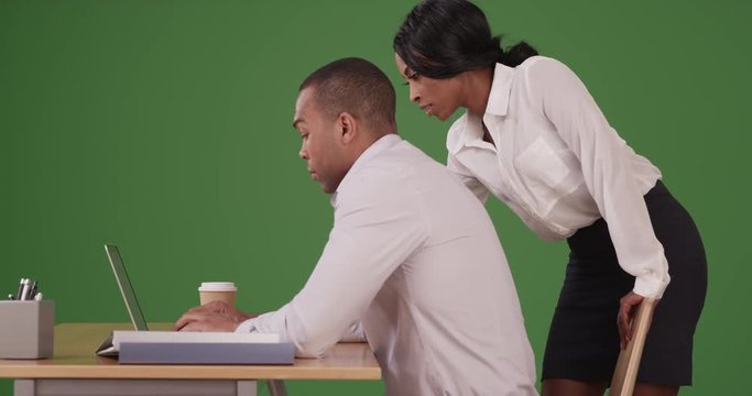 African American businessman and businesswoman working together as team on green screen. On green screen to be keyed or composited.