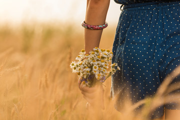 Girl in a wheat-field with bouquet of flowers.