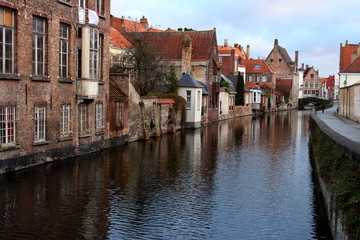 Fototapeta na wymiar Old town Brugge (Bruges), Belgium. Medieval buildings exterior with tiled roofs and reflection in river. Brick ancient houses and walls. Medieval architecture in Europe while travel. Winter Brugge.