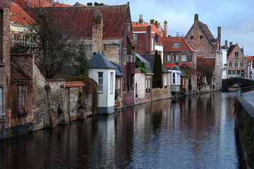 Fototapeta na wymiar Old town Brugge (Bruges), Belgium. Medieval buildings exterior with tiled roofs and reflection in river canal. Brick ancient houses and walls. Medieval architecture in Europe while travel. 