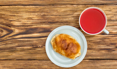 Cup of tea and saucer with sweet bun on the table. Top view.