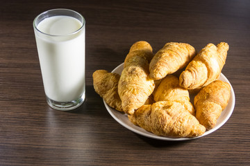 Glass of milk and fresh croissants on wooden table