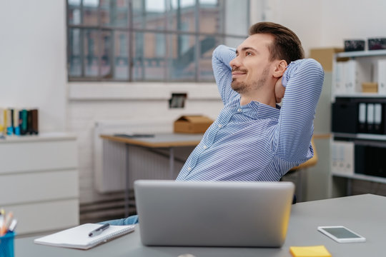 Young happy man relaxing in chair at office