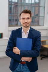 Young man standing with files in office