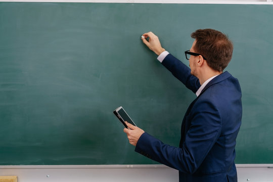 Male teacher writing on a chalkboard