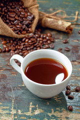 Warm coffee cup with roasted beans on rustic table