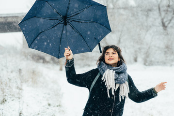 A cute young girl holds umbrellas in the hands of the winter season