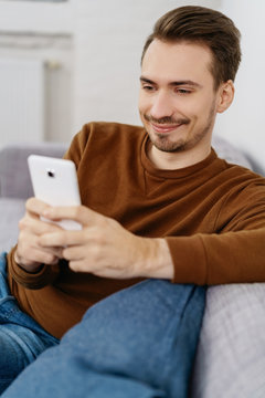 Young smiling man using smartphone at home