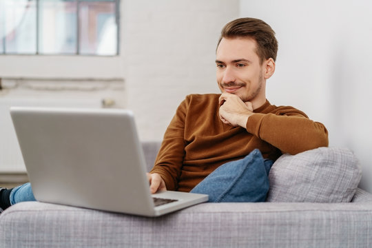 Young man sitting with laptop on sofa