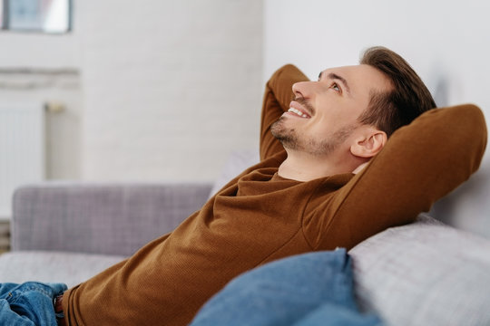 Young smiling man relaxing on sofa at home