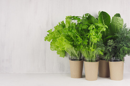 Different fresh greens for spring salad on white wooden background, interior, copy space.