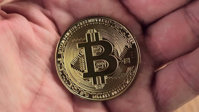 Bitcoin cryptocurrency in hands. Man holding BTC golden coin as symbol of electronic virtual money for web banking and international network payment