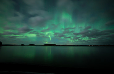 Fototapeta na wymiar Northern lights dancing over calm lake in Farnebofjarden national park in Sweden.