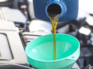 Close up pouring oil to car engine, maintenance concept