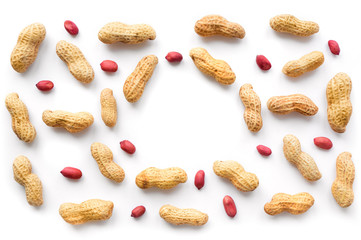 Creative peanut pattern with copy space. Isolated unpeeled groundnut and kernels. Top view.