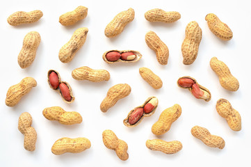 Creative peanut pattern. Isolated unpeeled groundnut and kernels. Top view.