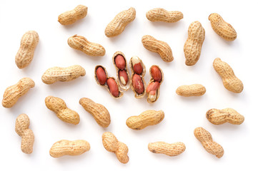 Isolated unpeeled groundnut and red seeds. Creative peanut pattern. Top view.