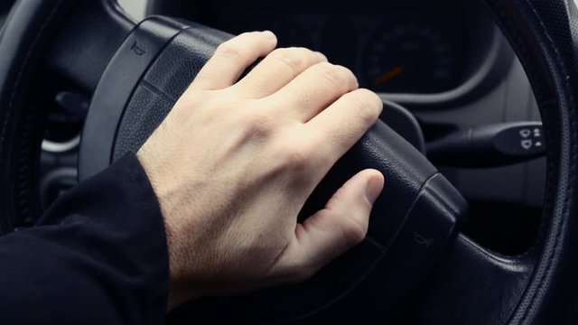 Male hand honking the car horn, man driving vehicle and beeping