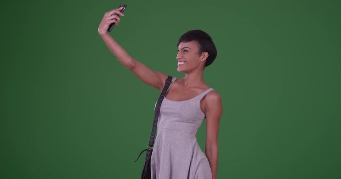 Woman blowing kiss and taking a selfie picture with smartphone on green screen. On green screen to be keyed or composited. 