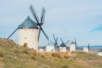 Rows of old white traditional windmills on the hill near Consuegra (Castilla La Mancha, Spain), a symbol of region and journeys of Don Quixote (Alonso Quijano) on cloudy day.