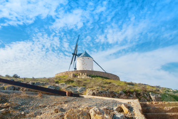 Old white traditional windmill on the hill near Consuegra (Castilla La Mancha, Spain), a symbol of region and journeys of Don Quixote (Alonso Quijano) on cloudy day.
