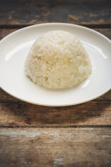 boiled round rice on a white plate, on a wooden surface