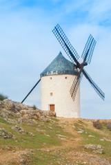 Fototapeta na wymiar Old white traditional windmill on the hill near Consuegra (Castilla La Mancha, Spain), a symbol of region and journeys of Don Quixote (Alonso Quijano) on cloudy day.