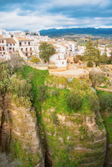 Fototapeta na wymiar A view to El Tajo Gorge Canyon, white traditional andalusian houses and mountains in Ronda, one of the most famous white villages (pueblos blancos) in Malaga province, Andalusia, Spain.