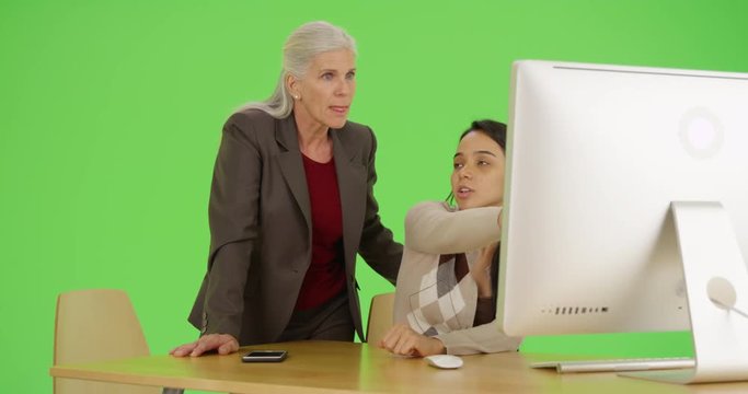 Two office workers use the computer on green screen. On green screen to be keyed or composited. 