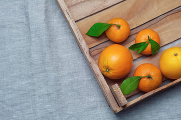 Oranges and tangerines in a wooden box on canvas. Orange juice.