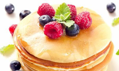 Sweet pancakes with raspberries and blueberies on a  white plate