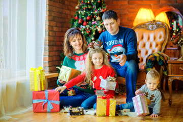 Fototapeta na wymiar a large friendly family gives each other presents sitting near the Christmas tree.