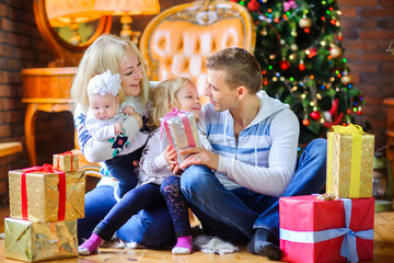 Fototapeta na wymiar Christmas morning, a big happy family gives each other presents, sitting near the Christmas tree.