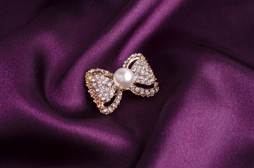 gold brooch bow with pearls and gems isolated on silk