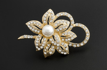 gold brooch flower with pearl isolated on black