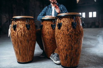 Male drummer plays on wooden drums in factory shop