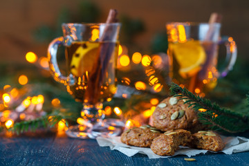 New Year's mulled wine in a glass on the background of twigs, candles and garlands.