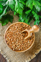 Raw buckwheat in wooden bowls and a scoop on sackcloth on a wooden background. Healthy diet food.