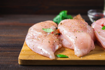 Raw chicken fillets on a cutting board against the background of a wooden table. Meat ingredients for cooking.