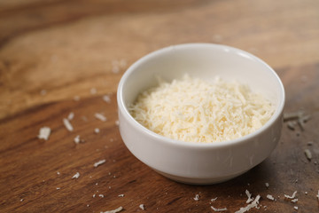 grated aged italian parmesan cheese in white bowl on table