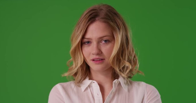 Close up of attractive Caucasian female dressed in white button down looking confidently at camera on green screen. On green to be keyed or composited. 